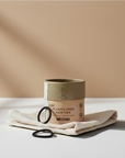 Zero Waste Outlet mini black organic cotton hair ties in a plastic-free cardboard tube on a white cloth surface