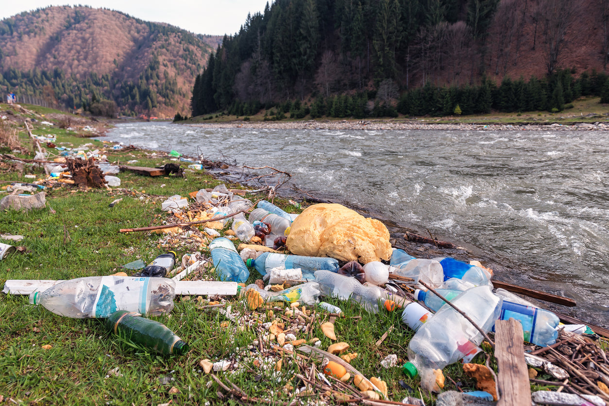 plastic pollution on side of beautiful riverbank